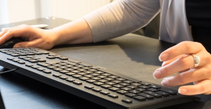 Arbeitsrecht-Anwalt am Schreibtisch mit Händen an der Tastatur.